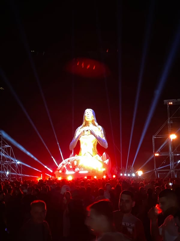 Crowds gather around glowing golden meditation statue at night festival