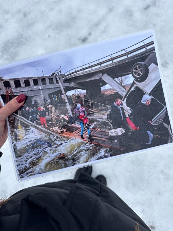 Person holds bridge destruction photo in snowy Irpin Ukraine