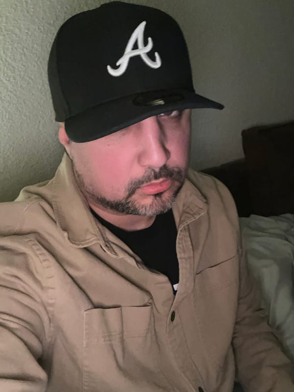 Man rests indoors wearing baseball cap in Cologne