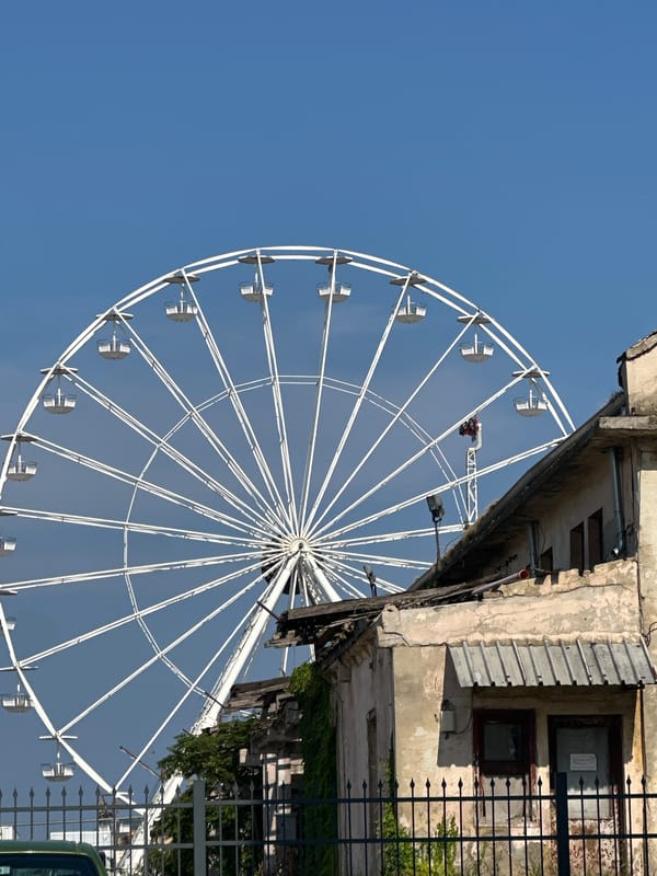 White Ferris wheel towers over a mixed urban neighborhood