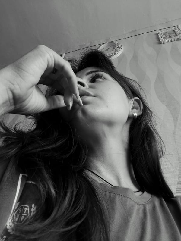 Black and white low-angle portrait, hand near lips, looking up