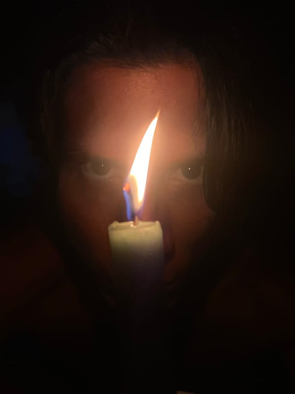 Person holds green candle in darkness in Venezuelan village