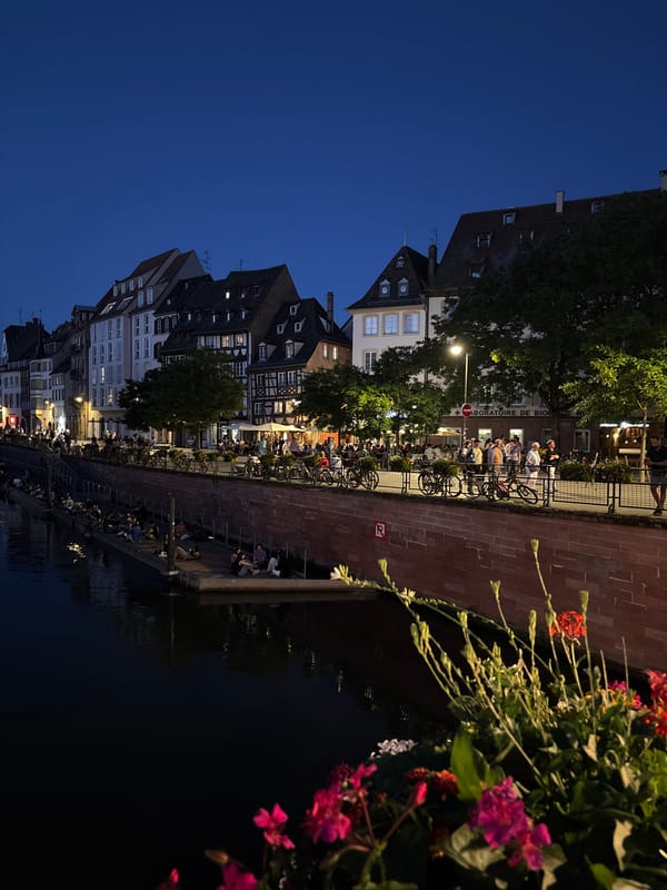 Evening gathering along illuminated Strasbourg canal waterfront