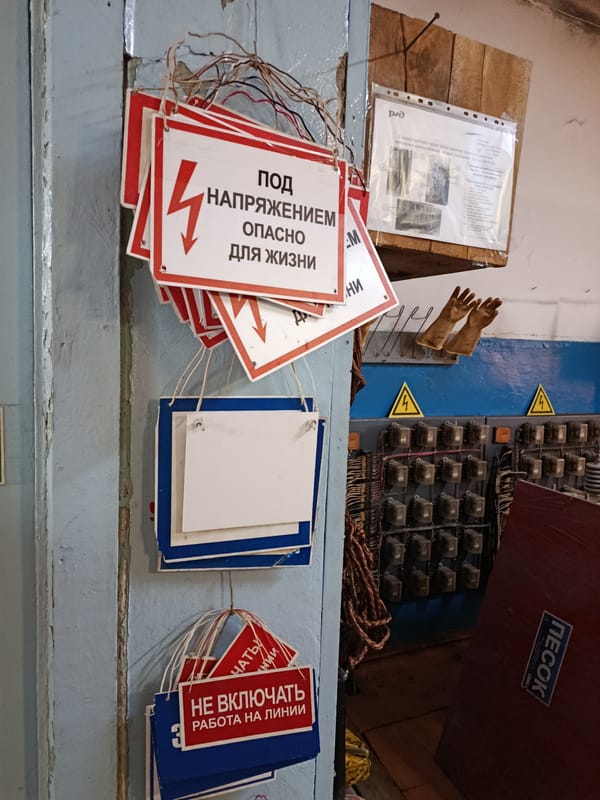Warning signs line a weathered wall in a Russian utility space.