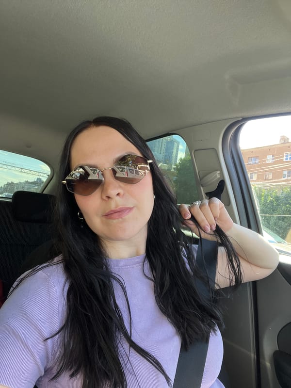 In-car selfie with reflective sunglasses, Voronezh streets in the background.