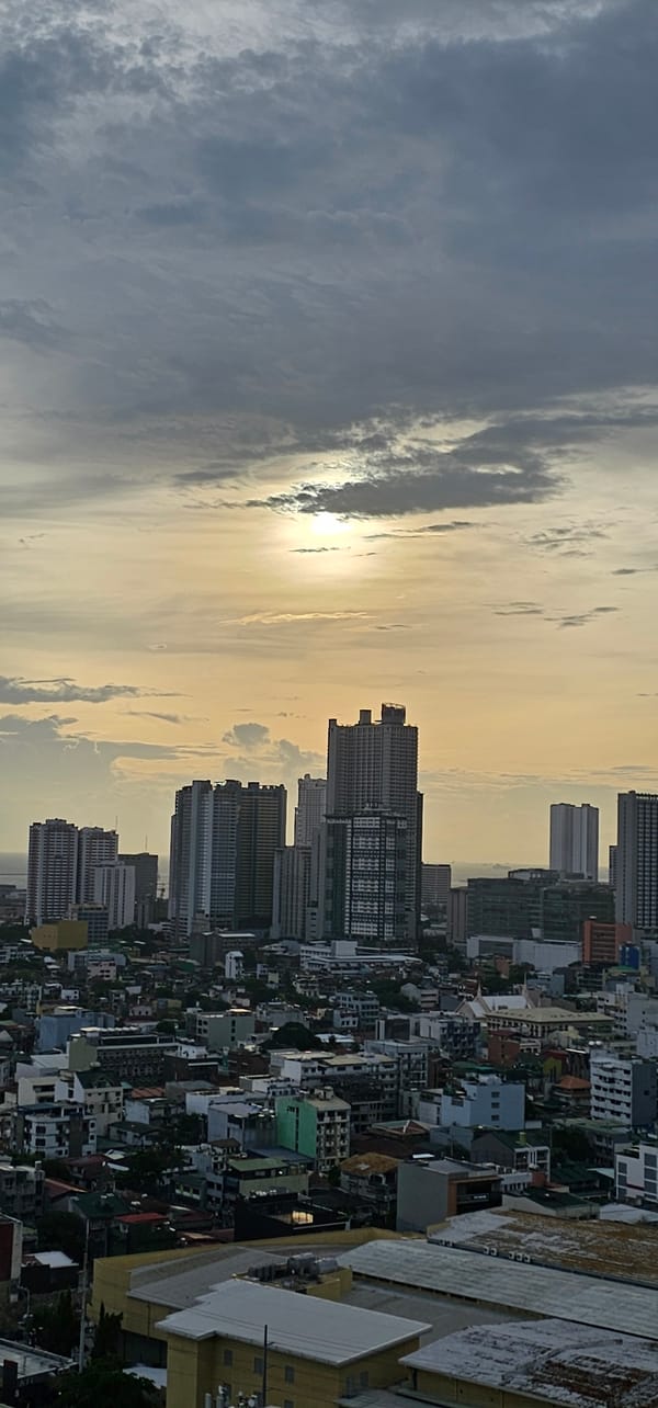 Makati skyline glows at dusk as a plane passes overhead