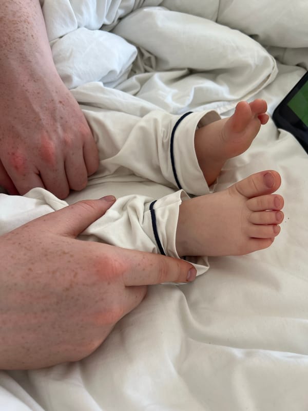 Adult tends to infant in white pajamas, Russia