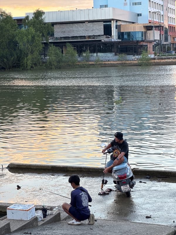 Fishing and moored boats along Surat Thani's riverside at dusk