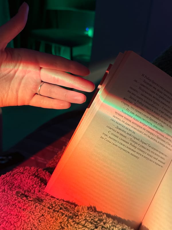 Person reads Russian book under rainbow lighting on blanket