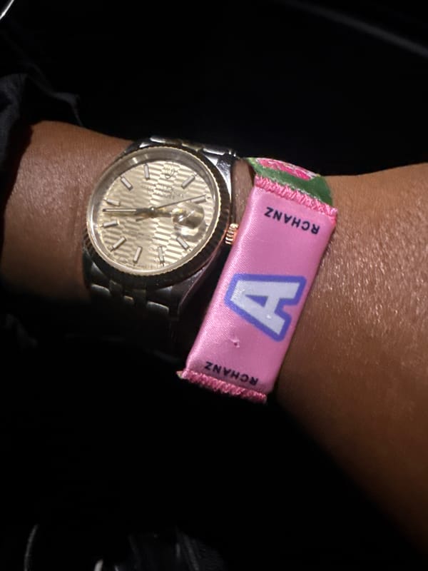 Person photographed wearing gold-faced watch with pink wristband in Indio