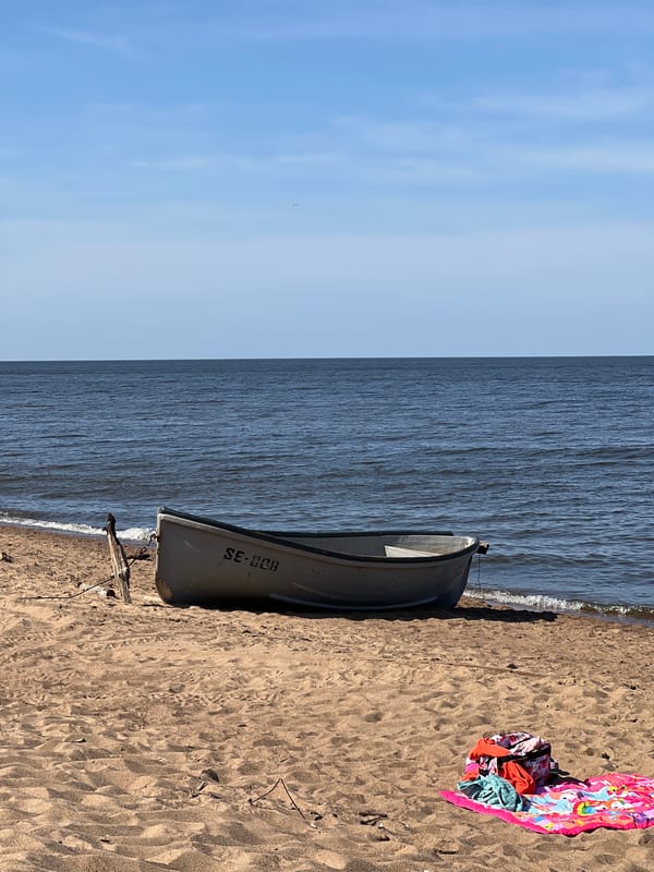 Quiet morning on the beach, rowboat ashore, feet in the surf