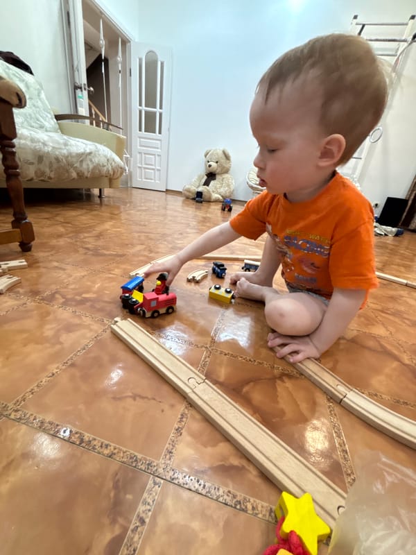 Child plays with wooden trains and Christmas decorations in Russia