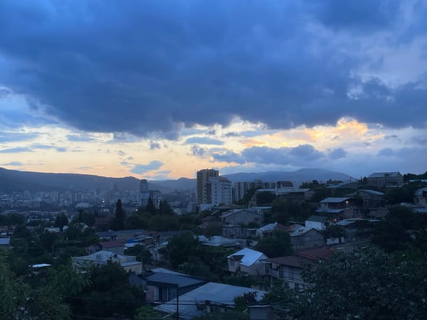 Tbilisi hillside at dusk, storm clouds rolling in