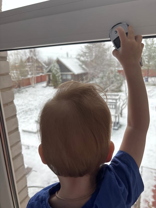 Child watches snowy backyard through window in Ферма, Russia