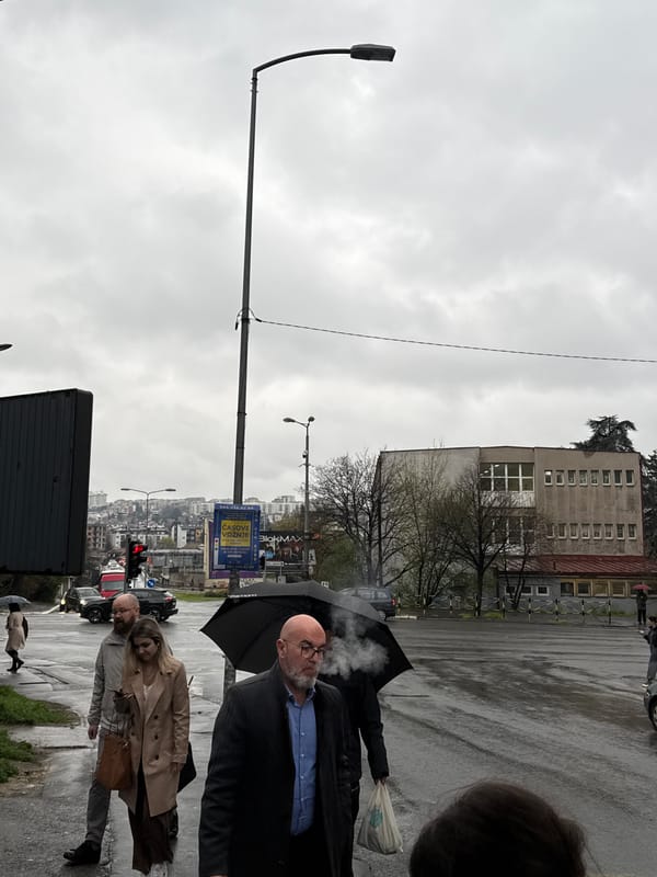 Pedestrians walk wet streets after rain in Belgrade suburb