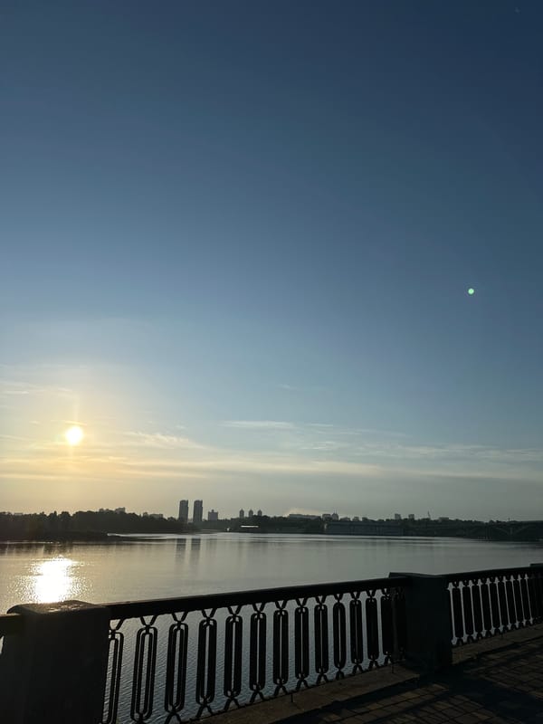 Sunrise along the Kyiv waterfront, ornate railing in frame