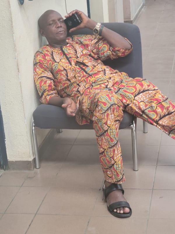 Man in traditional Ankara outfit photographed resting on chair