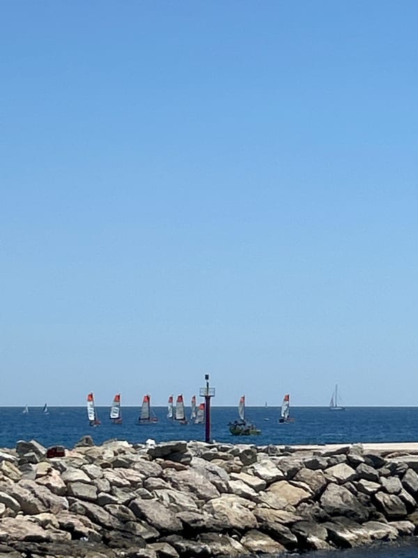 Barcelona waterfront: calm sea, sailboat, skyline on a clear morning