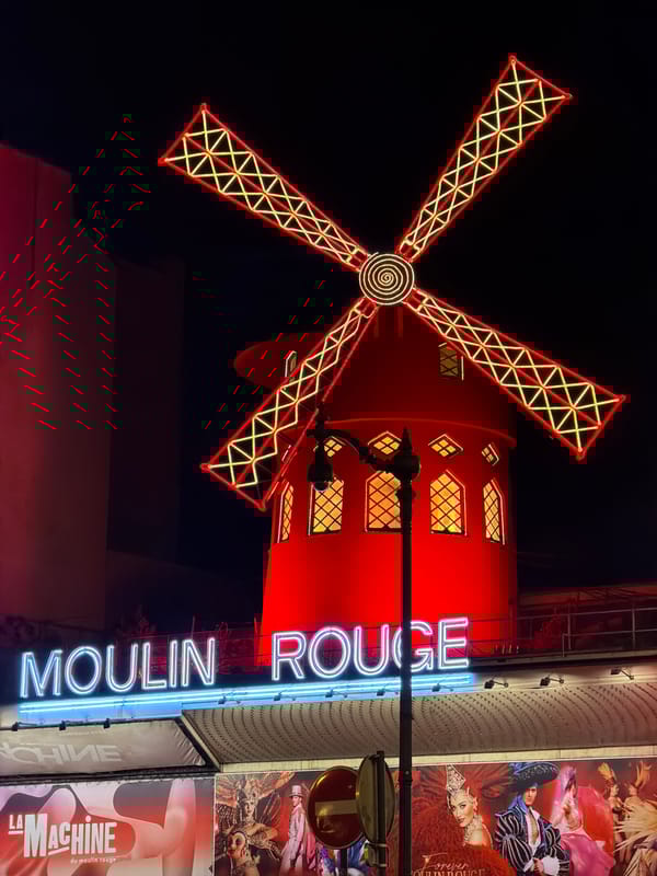 Evening street life documented around illuminated Moulin Rouge, Paris