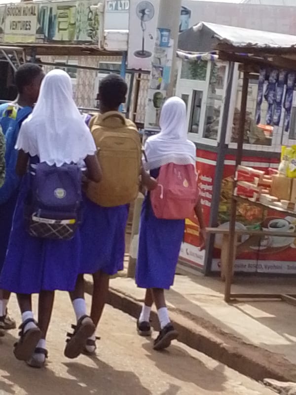 Typical street life unfolds in Tamale with students, delivery transport