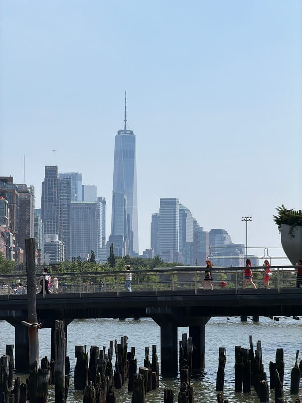 NYC skyline framed by weathered waterfront pilings on a clear day