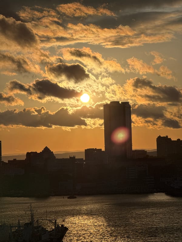 Golden sunrise illuminates cloudy skies over Vladivostok cityscape
