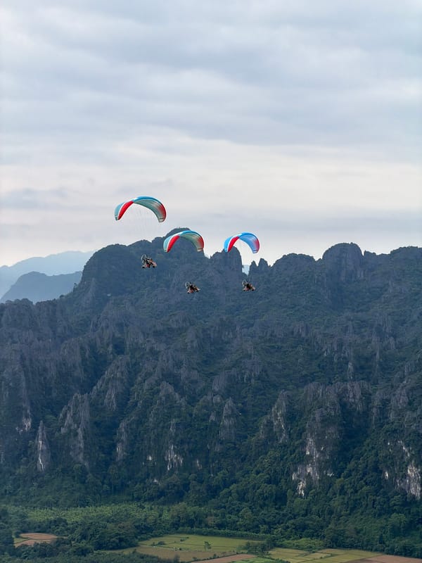 Paragliders with colorful wings over Laos mountain landscape
