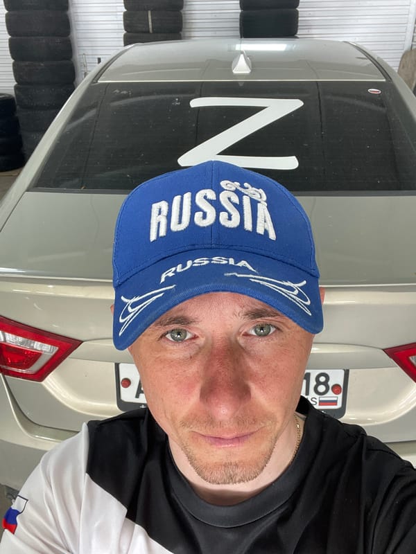 Man in Russia cap takes selfie with vehicle in Sarapul
