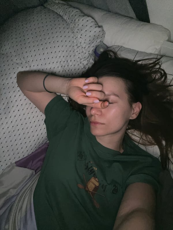 Woman rests in bed wearing Slytherin shirt in Limassol