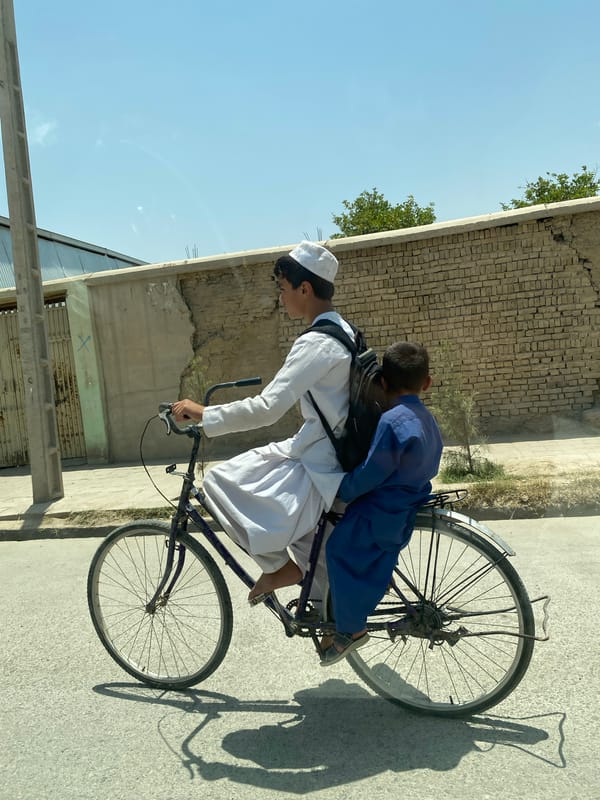 Sharing a bicycle on a paved Kandahar street