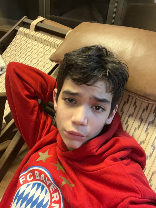 Person in Bayern Munich hoodie relaxes on leather seating