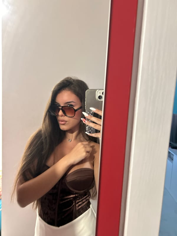 Mirror selfie showing a velvet corset and sunglasses look