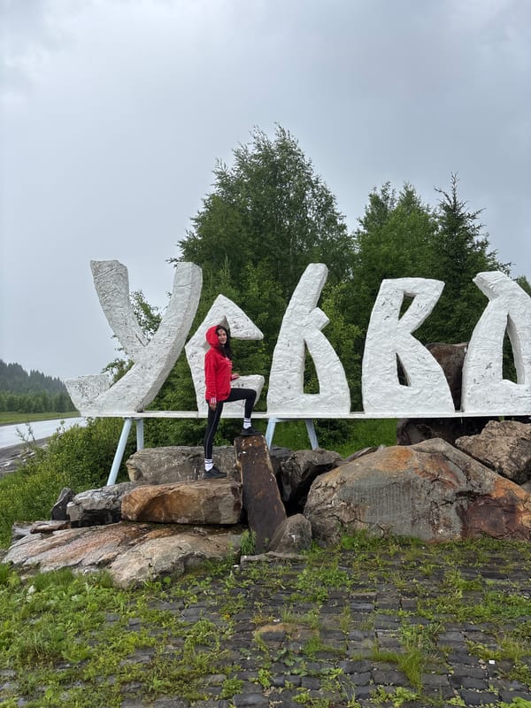 Women pose for photos at Gremyachinsk town sign
