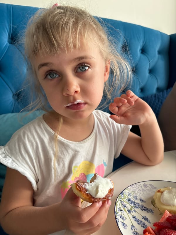 Girl enjoys cream pastry on couch in Russia