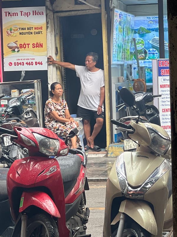 Wet streets and parked bikes outside Hanoi Old Quarter shops