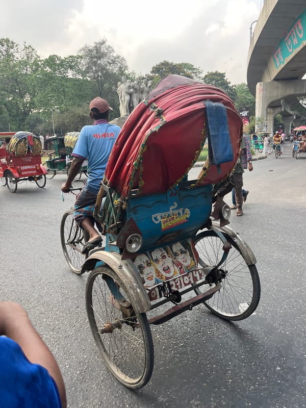 Rickshaws and decorated van share busy Dhaka street