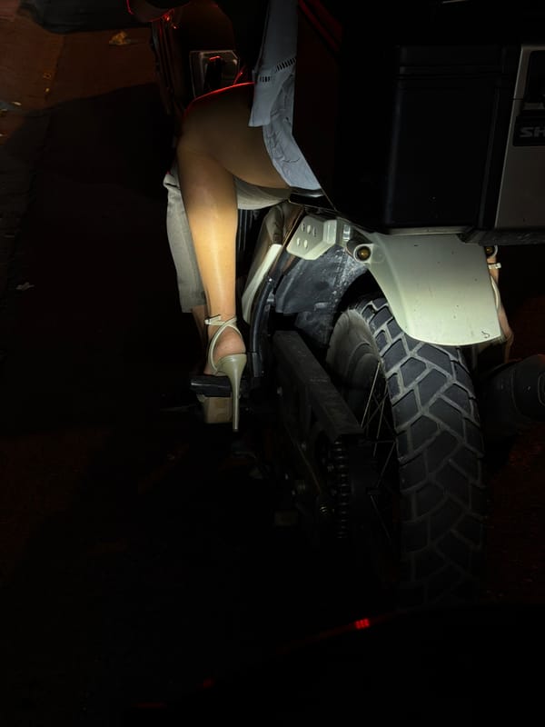 Parked motorcycle at night, heeled sandal on the footpeg, North Kuta