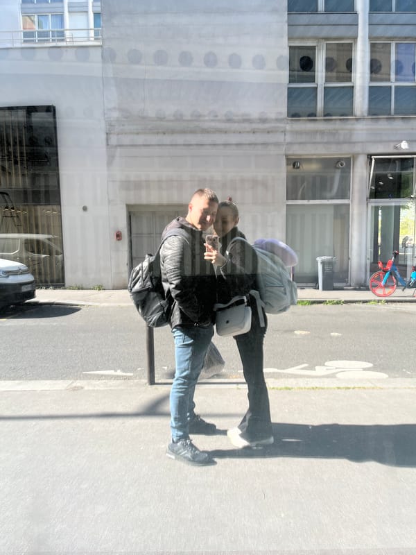 Couple reflected in Paris building glass on sunny afternoon