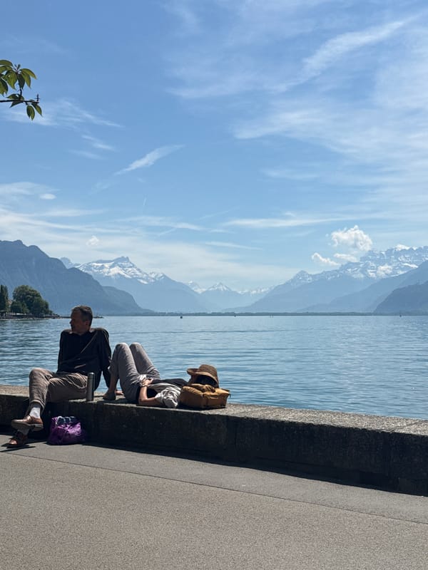 Two people sit by Lake Geneva in Vevey