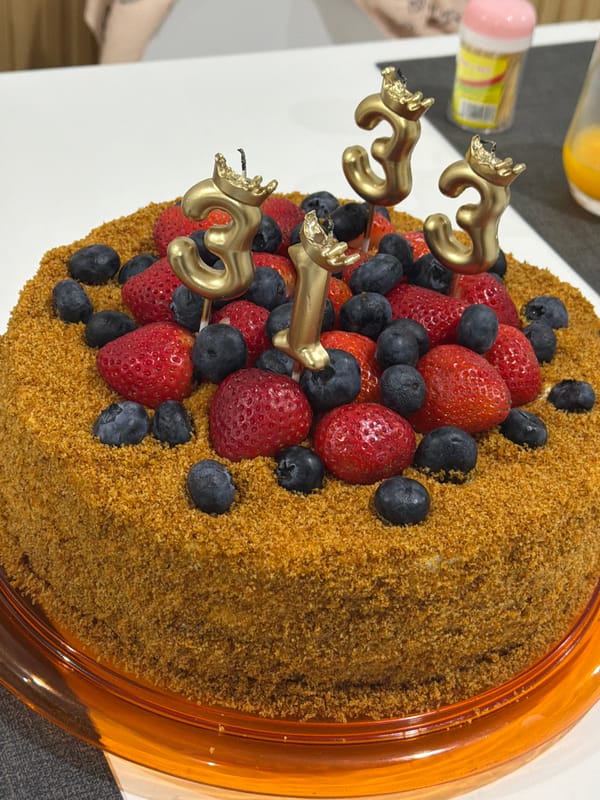 Third birthday cake with berry toppings and gold candles, Kathu