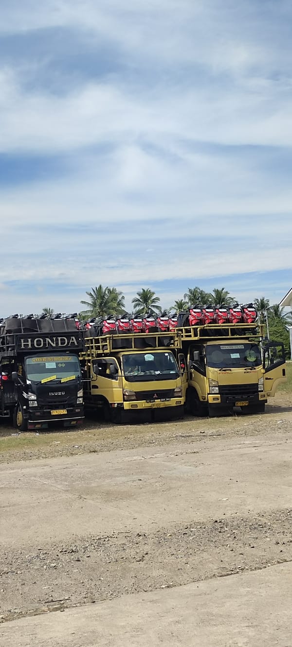 Honda scooter delivery trucks parked near a mosque in Aceh