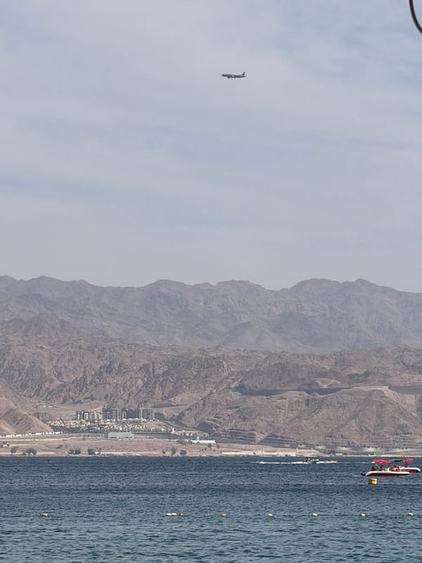 Boys paddleboard in Eilat waters amid mountain backdrop