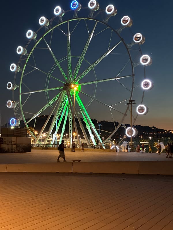 Ferris wheel glowing over Barcelona's waterfront at dusk
