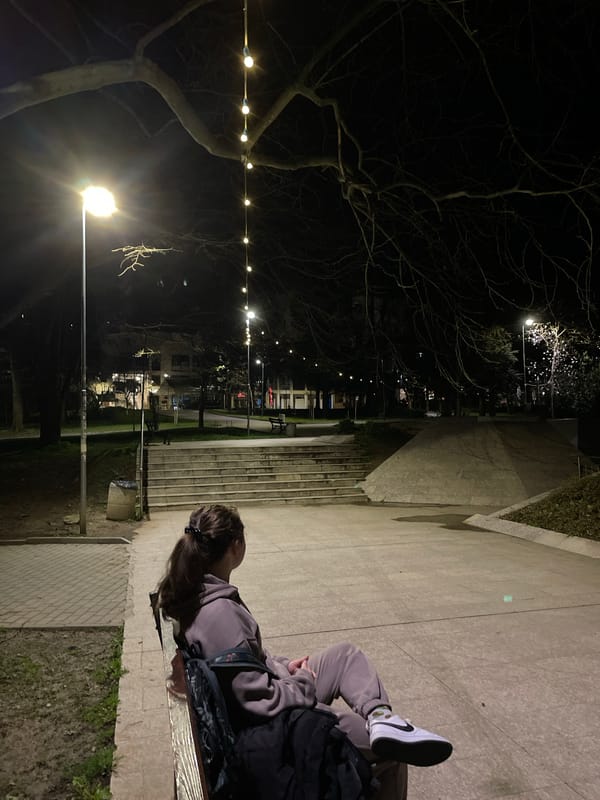 Woman sits in illuminated park during evening in Veliko Tarnovo