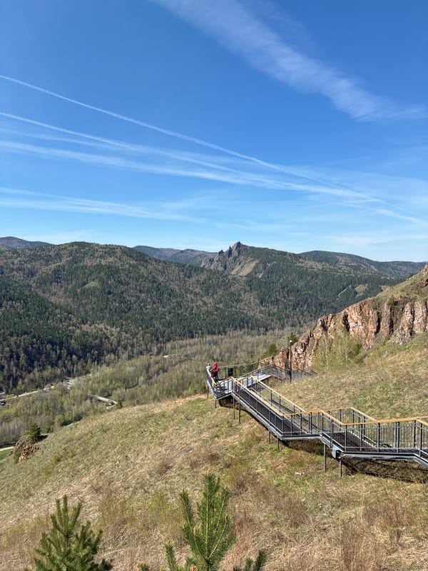 Mountain hikers climb metal stairs amid rocky terrain