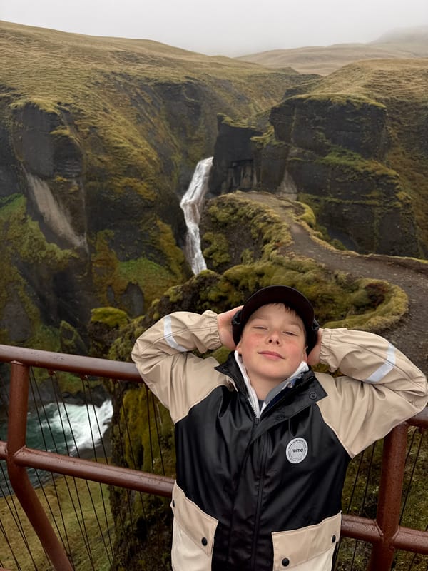 Tourists document moss-covered canyon waterfalls in Kirkjubæjarklaustur, Iceland