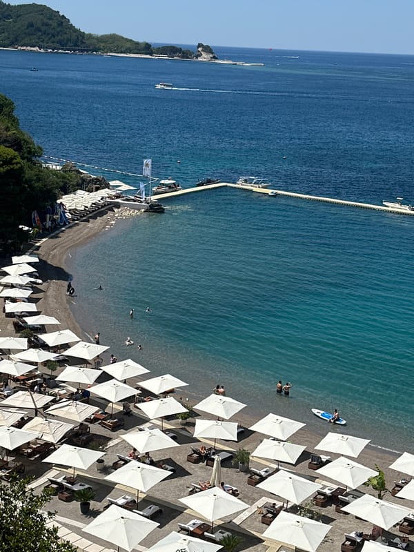 Budva beach and a decorated teal sign, Montenegro