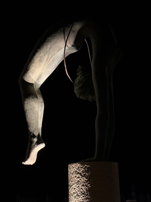 Moonlit beach and bronze acrobat statue on a Latina night