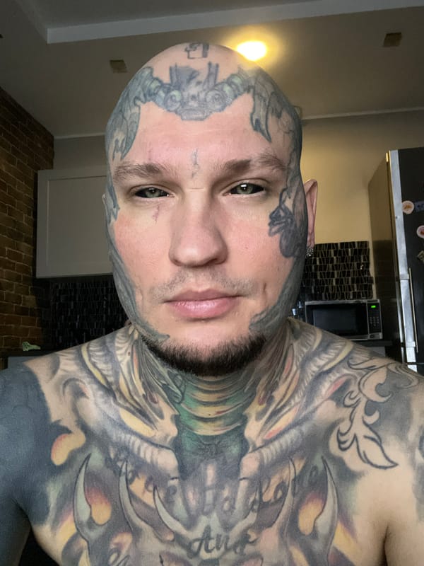 Tattooed man poses for kitchen photograph in Kudrovo