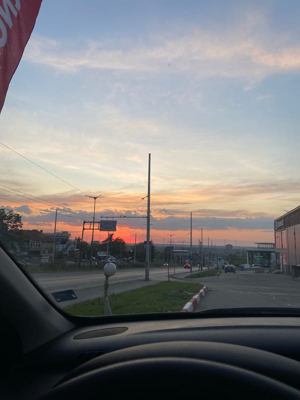 Urban sunset observed from vehicle shows colorful sky gradient